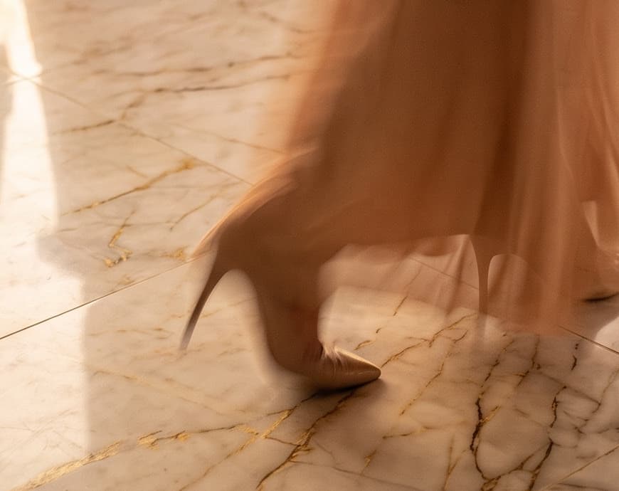 A shopper crossing veined marble, her skirt caught in motion