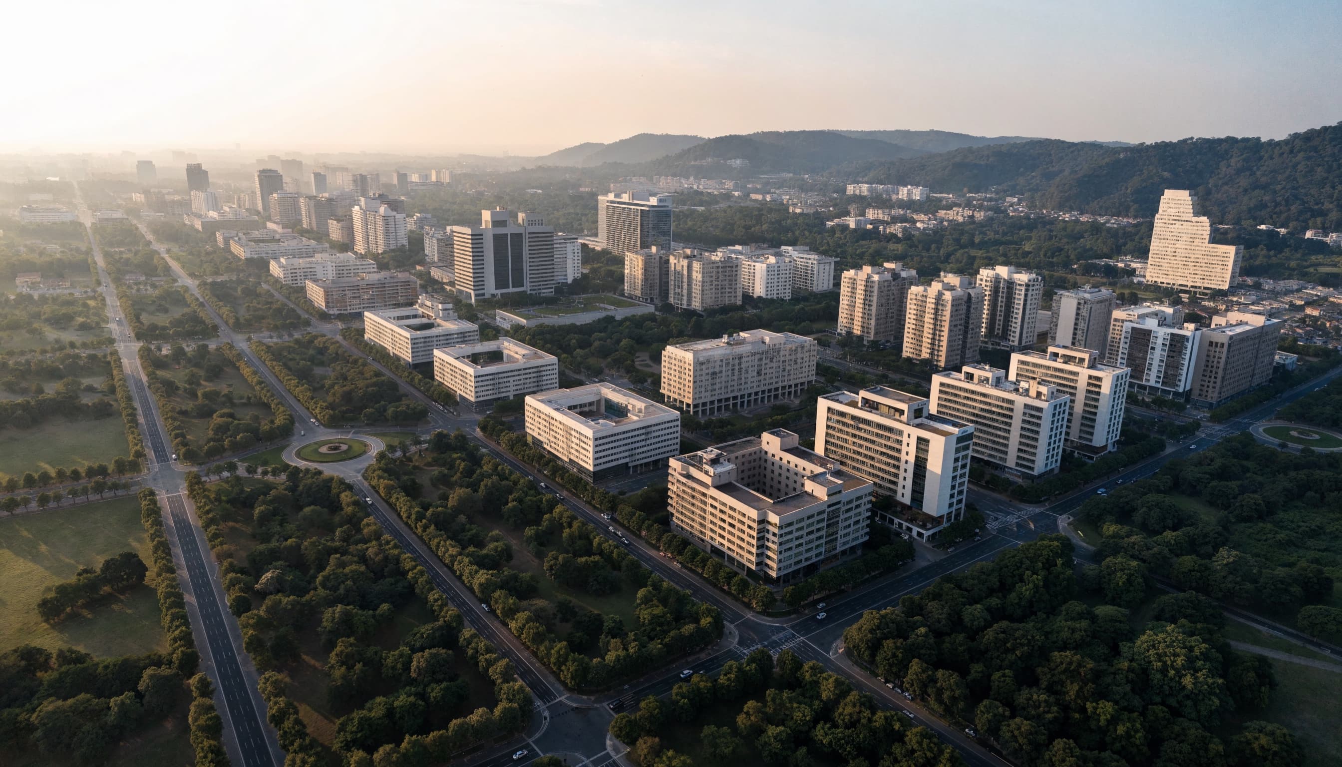 A modern capital at golden hour: wide tree lined boulevards, contemporary buildings and hills along the horizon