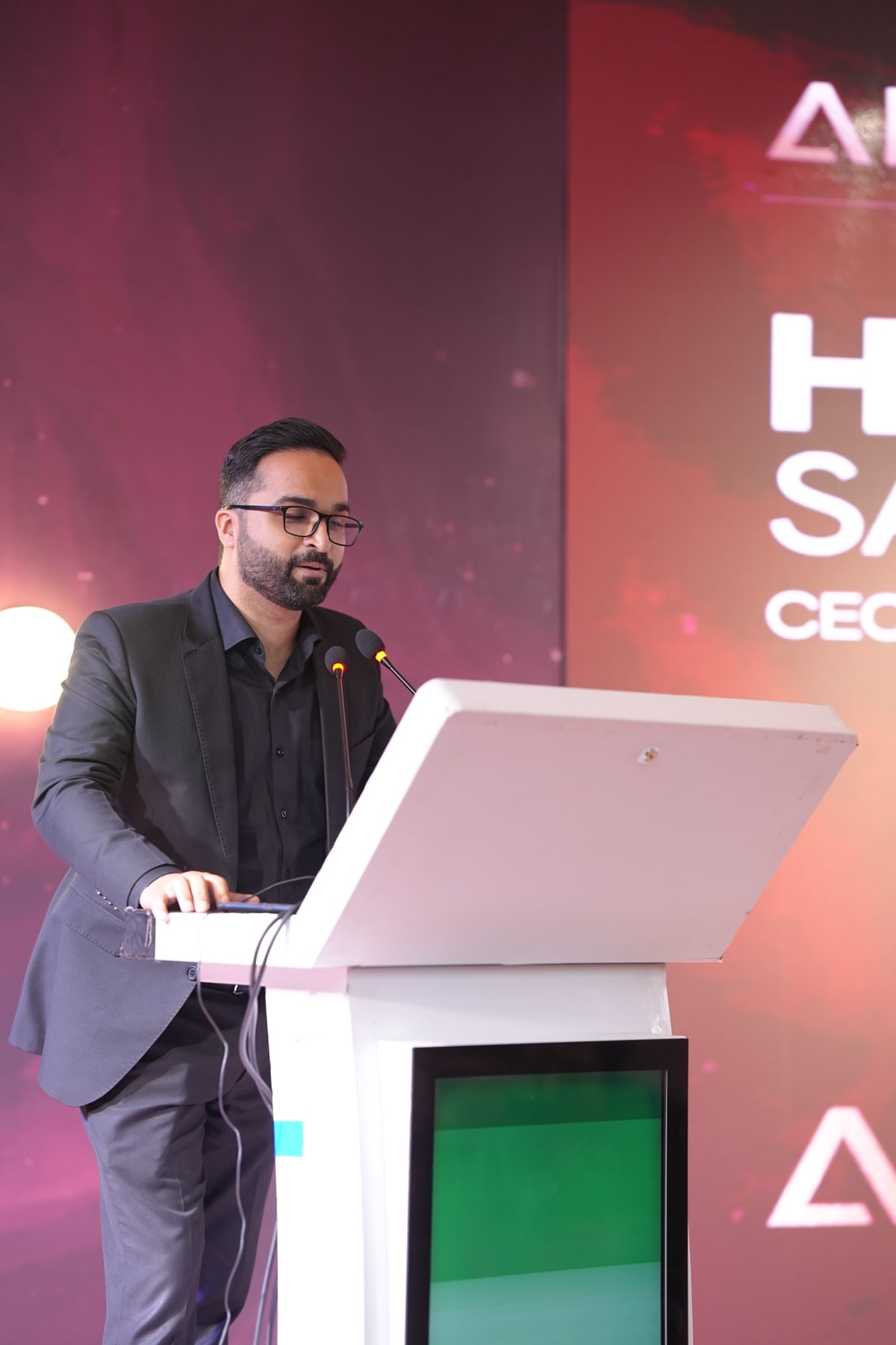 A speaker addressing the audience from the podium, the Afson identity lit behind him