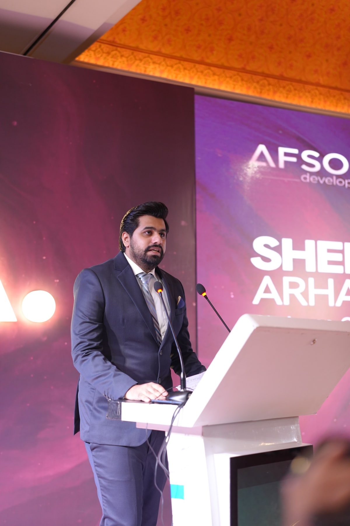 A speaker at the podium as the screen introduces the sales and marketing partner